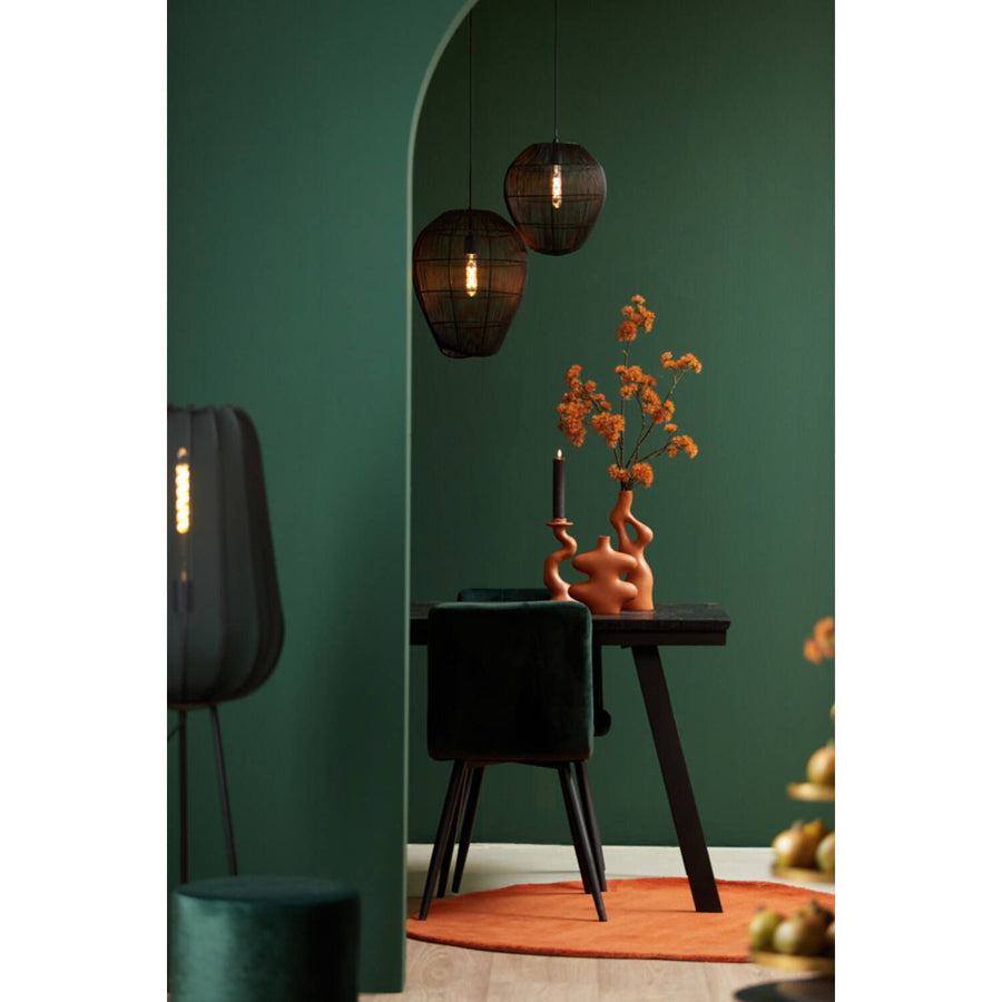 Interieur met donkergroene muren, zwart meubilair en oranje accenten, waaronder hanglampen.