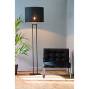 Zwarte staande lamp en stoel in een kamer met een potplant.