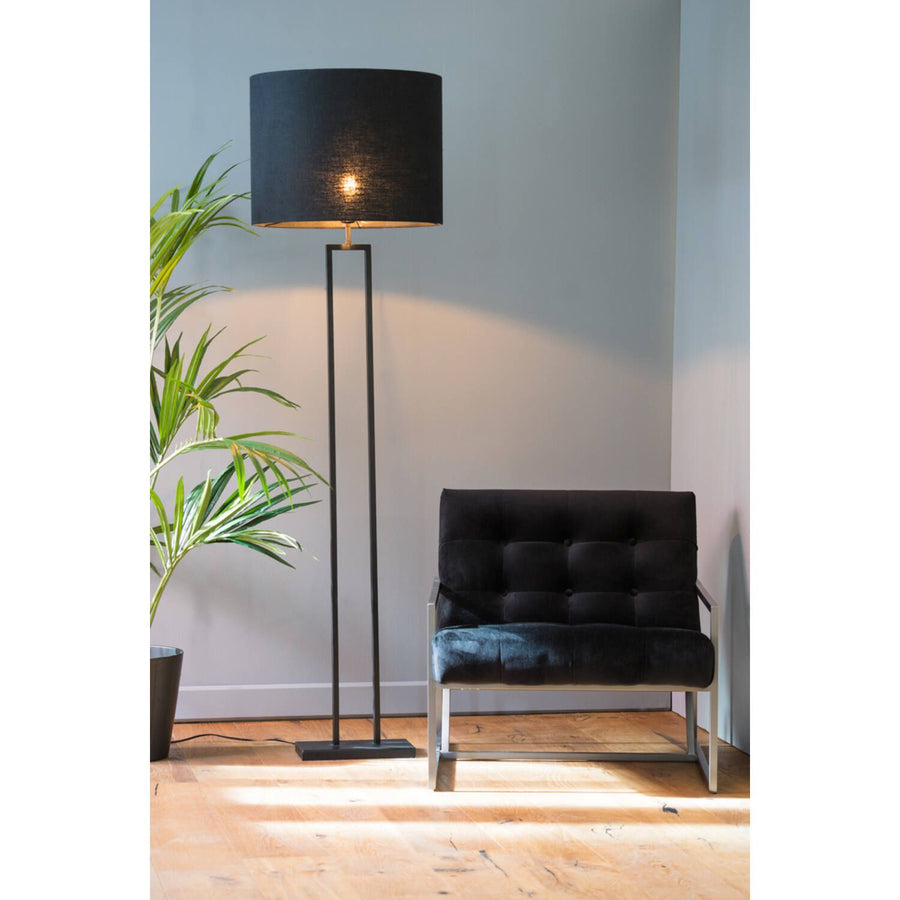 Zwarte staande lamp en stoel in een kamer met een potplant.