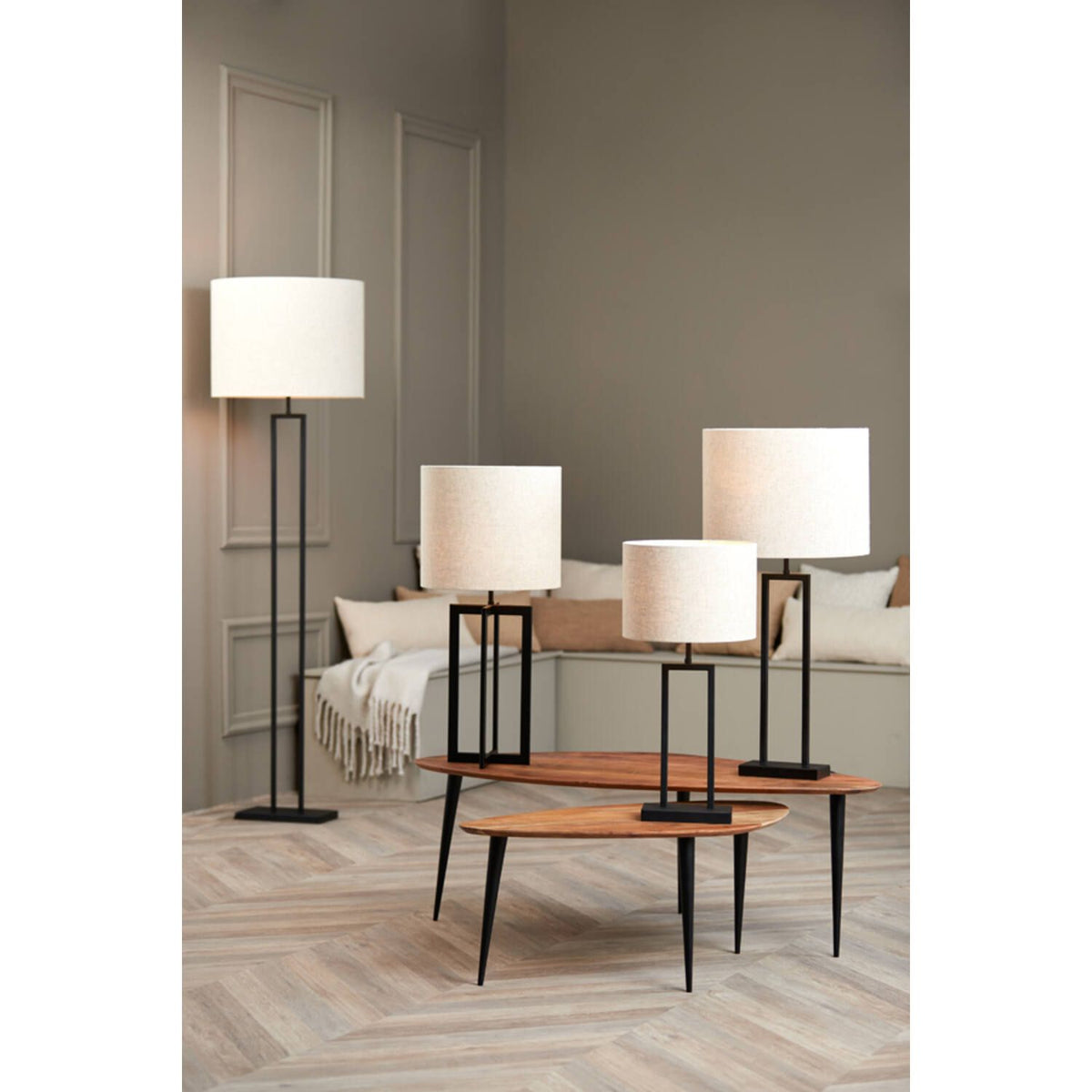 Vier lampen met zwarte frames en witte kappen in een woonkamer.