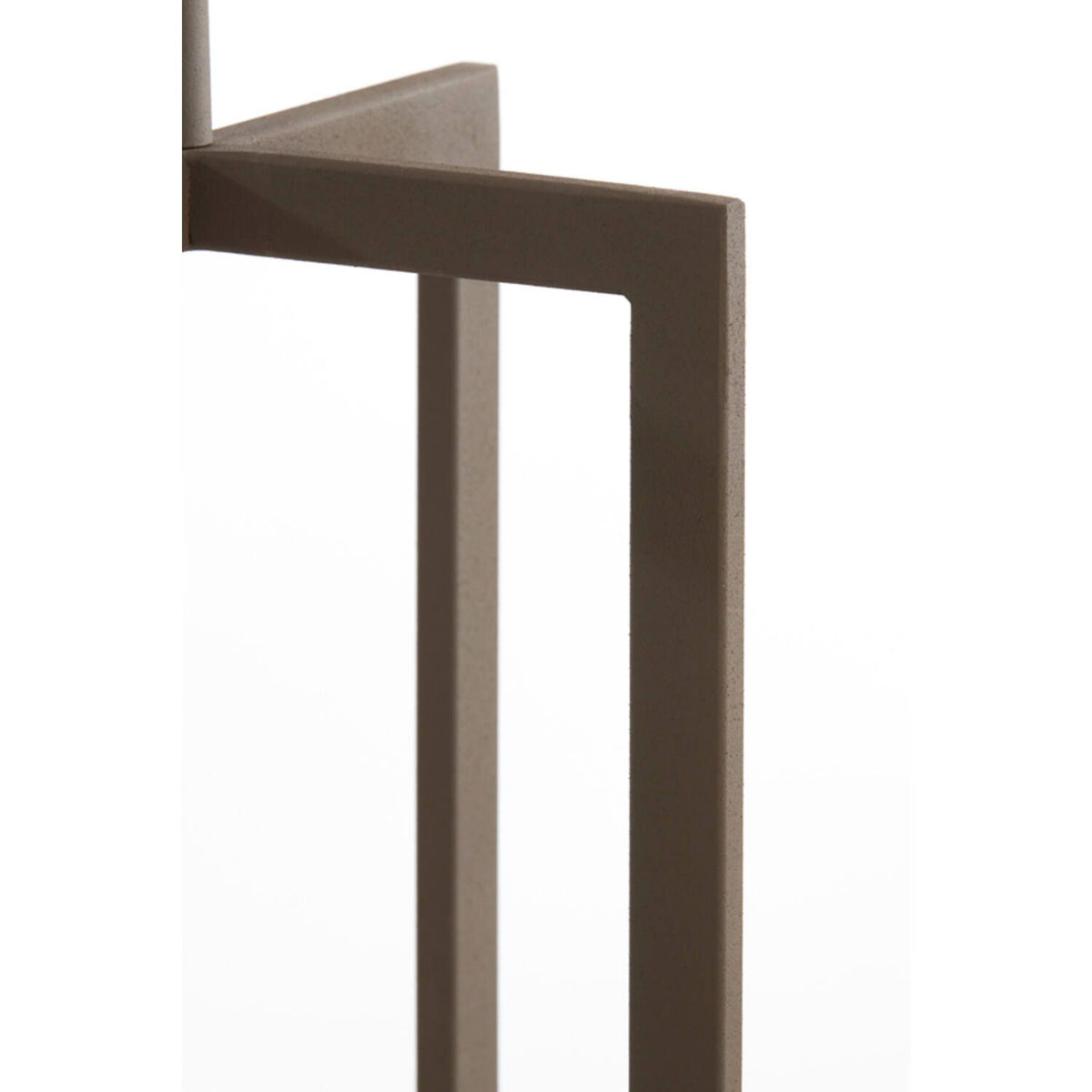 Detailopname van een bruin, geometrisch metalen meubelframe, mogelijk een tafelpoot, op een witte achtergrond.