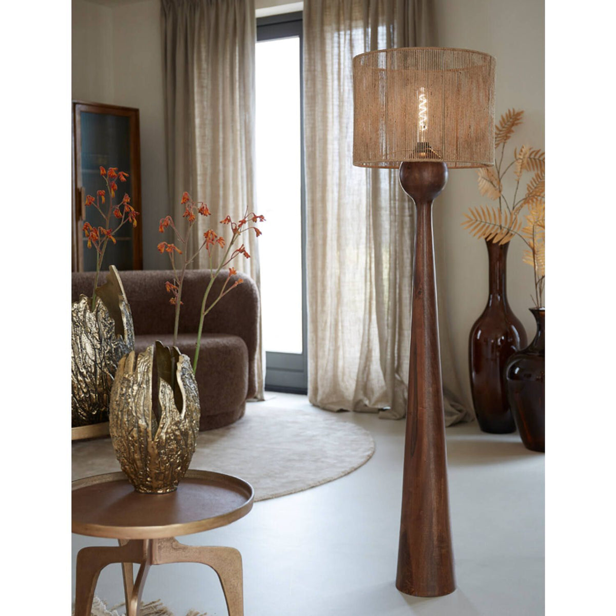Woonkamer met een staande lamp en decoratieve items in neutrale tinten.