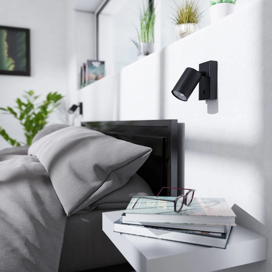 Zwarte wandlamp met cilindrische verstelbare GU10 spot, rechthoekige wandplaat en geïntegreerde schakelaar.